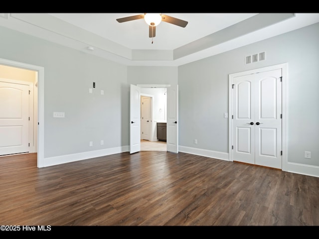 7024 Bonaventure St SW, Ocean Isle Beach, NC 28469 - unfurnished bedroom featuring dark wood-type flooring, a tray ceiling, baseboards, and ceiling fan