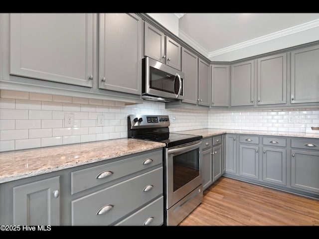 7024 Bonaventure St SW, Ocean Isle Beach, NC 28469 - kitchen featuring stainless steel appliances, gray cabinets, crown molding, decorative backsplash, and light wood-type flooring