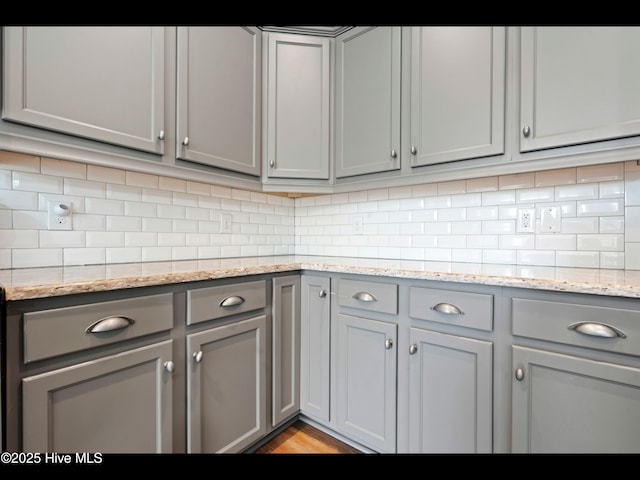 7024 Bonaventure St SW, Ocean Isle Beach, NC 28469 - kitchen with gray cabinets, decorative backsplash, light stone counters, and light wood-type flooring