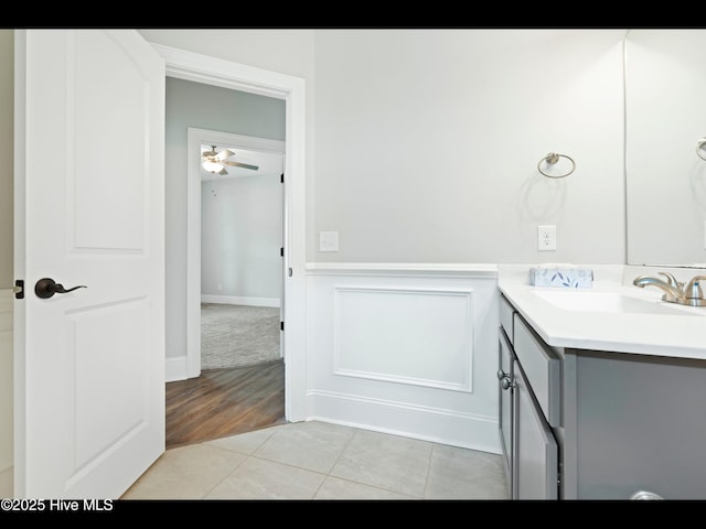 7024 Bonaventure St SW, Ocean Isle Beach, NC 28469 - bathroom featuring vanity, a ceiling fan, tile patterned flooring, and a wainscoted wall