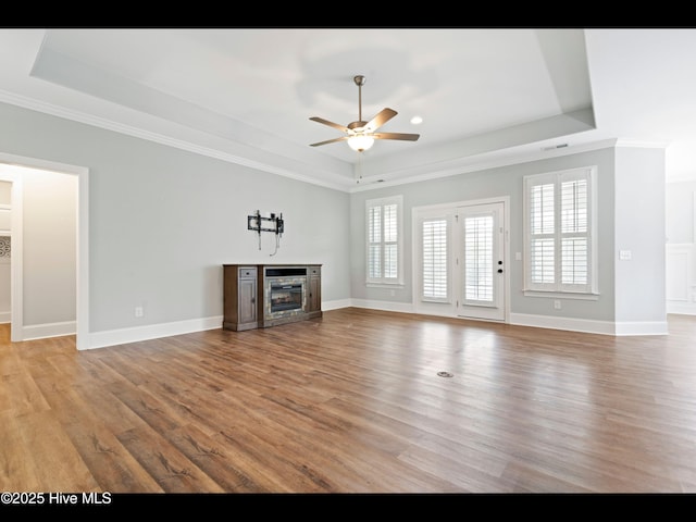 7024 Bonaventure St SW, Ocean Isle Beach, NC 28469 - unfurnished living room featuring a raised ceiling, a ceiling fan, a fireplace, light wood-style flooring, and ornamental molding