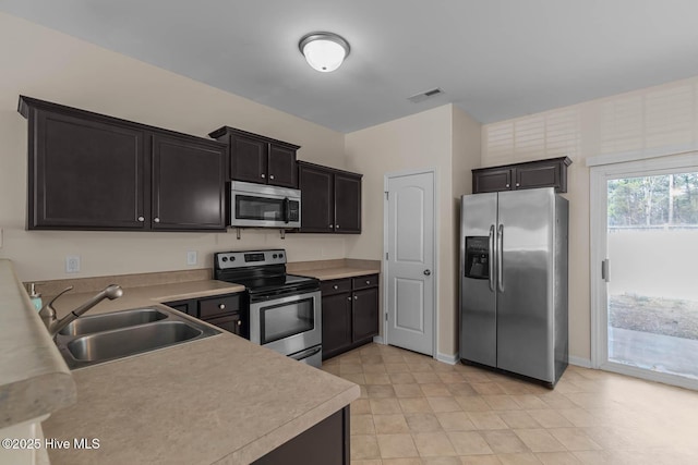 505 Oyster Rock Ln, Sneads Ferry, NC 28460 - kitchen with stainless steel appliances, a sink, light countertops, dark cabinets, and baseboards