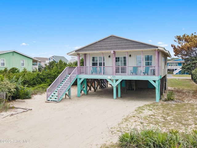 926 E Beach Dr, Oak Island, NC 28465 - raised beach house featuring covered porch, a carport, stairway, and driveway