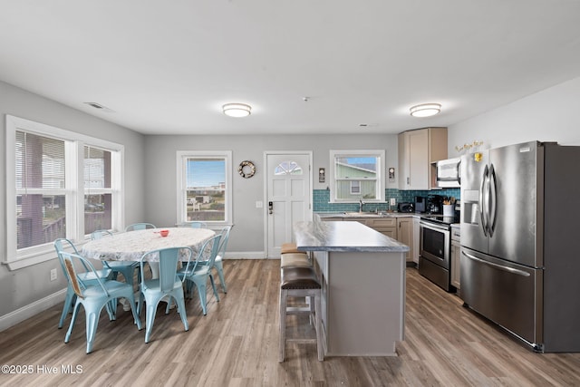 926 E Beach Dr, Oak Island, NC 28465 - kitchen featuring stainless steel appliances, light wood-type flooring, healthy amount of natural light, and decorative backsplash