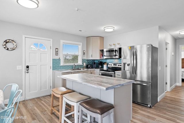 926 E Beach Dr, Oak Island, NC 28465 - kitchen featuring stainless steel appliances, light wood-type flooring, backsplash, light countertops, and a kitchen bar