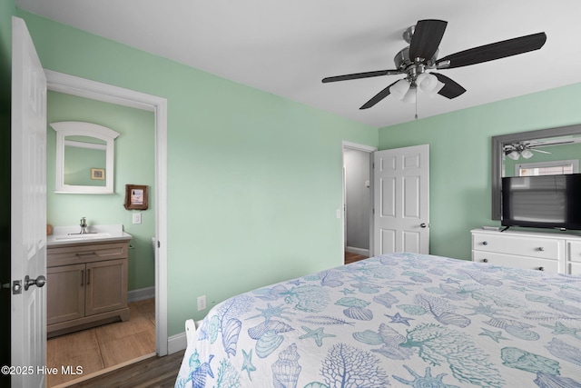 926 E Beach Dr, Oak Island, NC 28465 - bedroom with a sink, wood finished floors, baseboards, ceiling fan, and connected bathroom