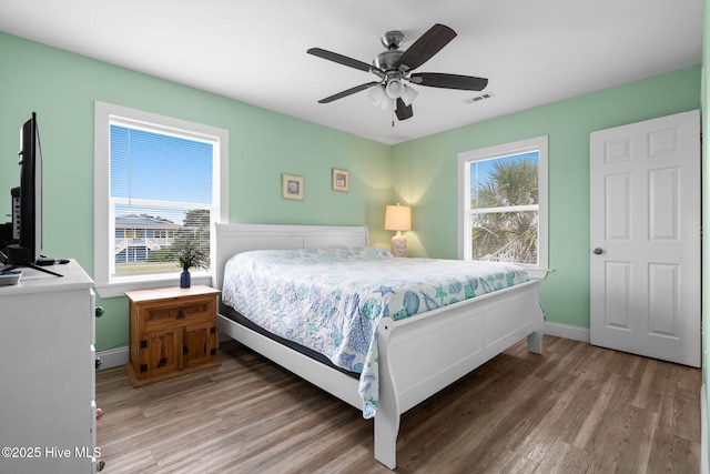 926 E Beach Dr, Oak Island, NC 28465 - bedroom featuring multiple windows, light wood finished floors, baseboards, and ceiling fan