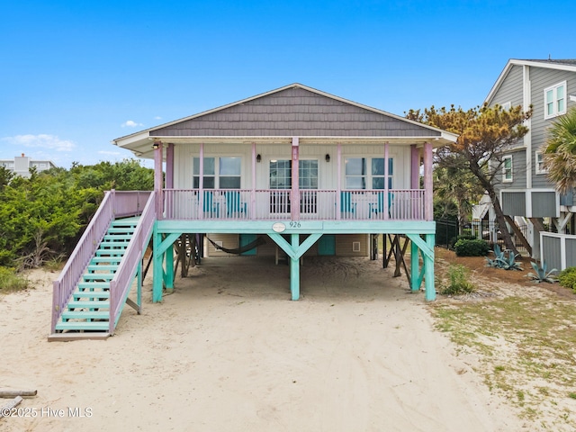 926 E Beach Dr, Oak Island, NC 28465 - raised beach house featuring a carport, stairway, a porch, and board and batten siding