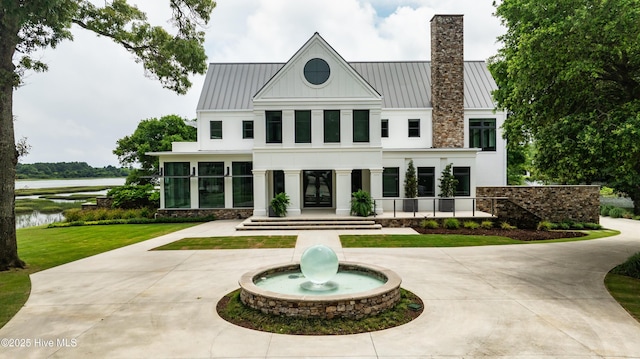 1064 Ocean Ridge Dr, Wilmington, NC 28405 - back of property featuring a standing seam roof, curved driveway, a water view, and a chimney