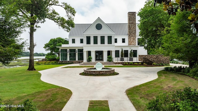 1064 Ocean Ridge Dr, Wilmington, NC 28405 - back of property featuring a water view, curved driveway, a lawn, a chimney, and a standing seam roof