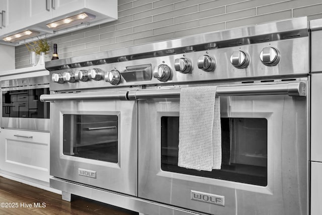 1064 Ocean Ridge Dr, Wilmington, NC 28405 - kitchen view of double oven range, backsplash, white cabinetry, and dark wood finished floors