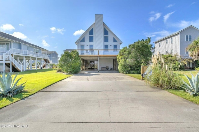 6707 Kings Lynn Dr, Oak Island, NC 28465 - view of front of house featuring a carport, stairway, a front lawn, driveway, and a chimney