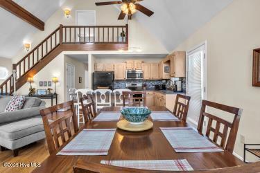 6707 Kings Lynn Dr, Oak Island, NC 28465 - dining space featuring a ceiling fan, high vaulted ceiling, stairway, wood finished floors, and baseboards