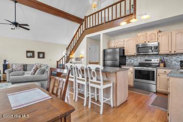 6707 Kings Lynn Dr, Oak Island, NC 28465 - kitchen with appliances with stainless steel finishes, ceiling fan, tasteful backsplash, a breakfast bar, and high vaulted ceiling