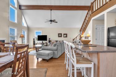 6707 Kings Lynn Dr, Oak Island, NC 28465 - living room featuring wood finished floors, a ceiling fan, beamed ceiling, stairway, and high vaulted ceiling
