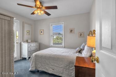 6707 Kings Lynn Dr, Oak Island, NC 28465 - carpeted bedroom with multiple windows and a ceiling fan