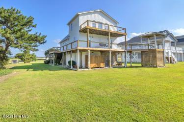 6707 Kings Lynn Dr, Oak Island, NC 28465 - rear view of house featuring a balcony, a lawn, stairway, and a wooden deck