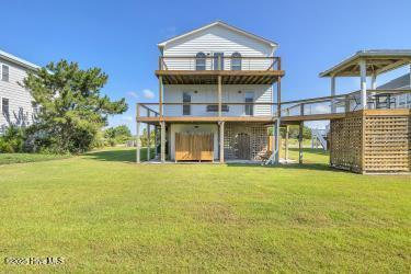 6707 Kings Lynn Dr, Oak Island, NC 28465 - rear view of property with a wooden deck, a lawn, and stairway