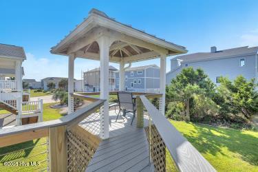 6707 Kings Lynn Dr, Oak Island, NC 28465 - wooden deck with a lawn and a gazebo