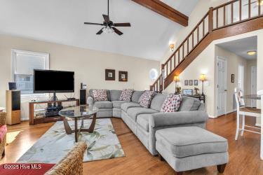 6707 Kings Lynn Dr, Oak Island, NC 28465 - living room featuring a ceiling fan, high vaulted ceiling, stairway, wood finished floors, and beamed ceiling