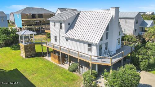 6707 Kings Lynn Dr, Oak Island, NC 28465 - rear view of property featuring a yard, a chimney, metal roof, and a deck
