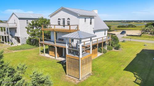 6707 Kings Lynn Dr, Oak Island, NC 28465 - rear view of house with a wooden deck and a lawn