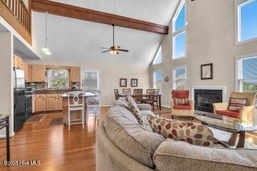 6707 Kings Lynn Dr, Oak Island, NC 28465 - living area with high vaulted ceiling, ceiling fan, dark wood-style floors, a fireplace, and beamed ceiling