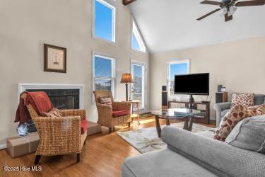 6707 Kings Lynn Dr, Oak Island, NC 28465 - living area featuring a glass covered fireplace, high vaulted ceiling, a ceiling fan, and wood finished floors