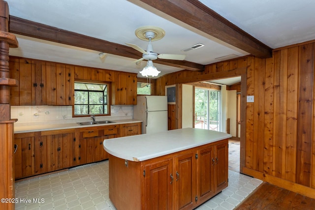 1772 NC-5 Hwy, Aberdeen, NC 28315 - kitchen featuring freestanding refrigerator, a sink, beam ceiling, tasteful backsplash, and brown cabinetry