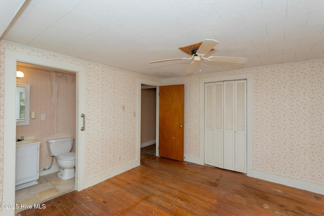 1772 NC-5 Hwy, Aberdeen, NC 28315 - unfurnished bedroom with hardwood / wood-style floors, wallpapered walls, connected bathroom, a closet, and ceiling fan