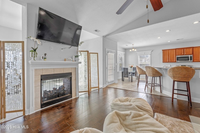 100 Little Acorn Trl, Moyock, NC 27958 - living area featuring vaulted ceiling, a ceiling fan, dark wood finished floors, a tiled fireplace, and baseboards