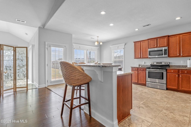 100 Little Acorn Trl, Moyock, NC 27958 - kitchen featuring stainless steel appliances, a breakfast bar area, recessed lighting, brown cabinets, and a kitchen island