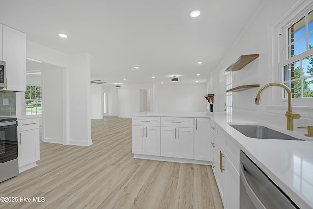 3825 Canterbury Rd, Wilmington, NC 28403 - kitchen featuring stainless steel appliances, a sink, open shelves, light wood-style flooring, and white cabinets