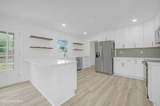 3825 Canterbury Rd, Wilmington, NC 28403 - kitchen featuring appliances with stainless steel finishes, open shelves, a peninsula, light wood-style flooring, and light countertops