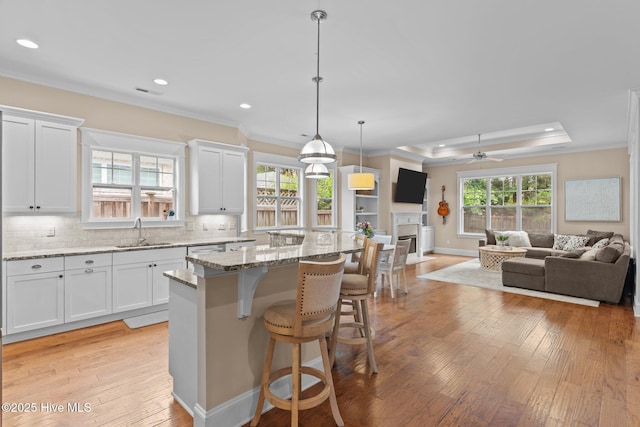 712 Tanbridge Rd, Wilmington, NC 28405 - kitchen featuring a sink, ornamental molding, open floor plan, light wood-style floors, and a kitchen bar