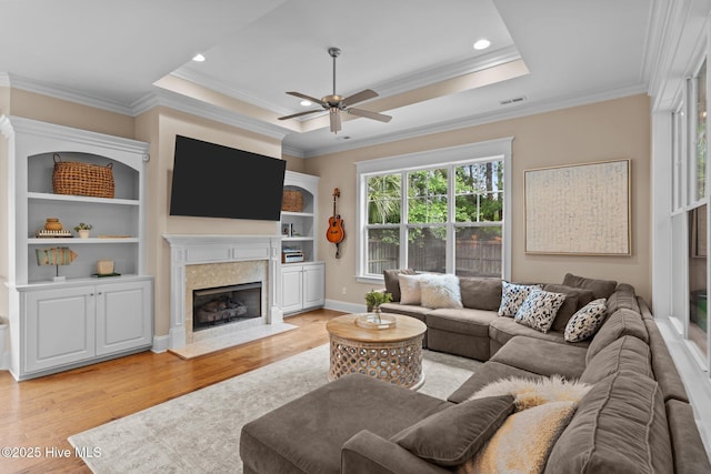 712 Tanbridge Rd, Wilmington, NC 28405 - living room featuring a ceiling fan, light wood-type flooring, a high end fireplace, crown molding, and a tray ceiling