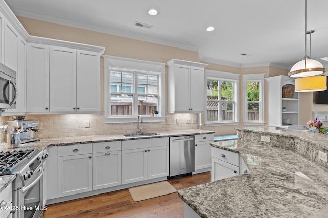 712 Tanbridge Rd, Wilmington, NC 28405 - kitchen with appliances with stainless steel finishes, a sink, white cabinets, wood finished floors, and crown molding