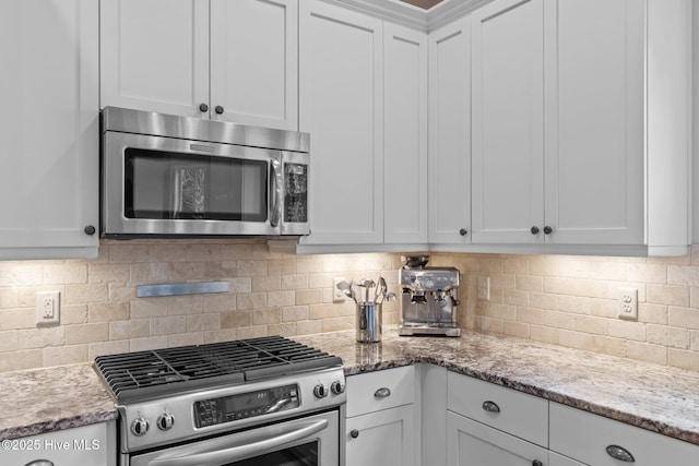 712 Tanbridge Rd, Wilmington, NC 28405 - kitchen with appliances with stainless steel finishes, white cabinets, decorative backsplash, and light stone counters