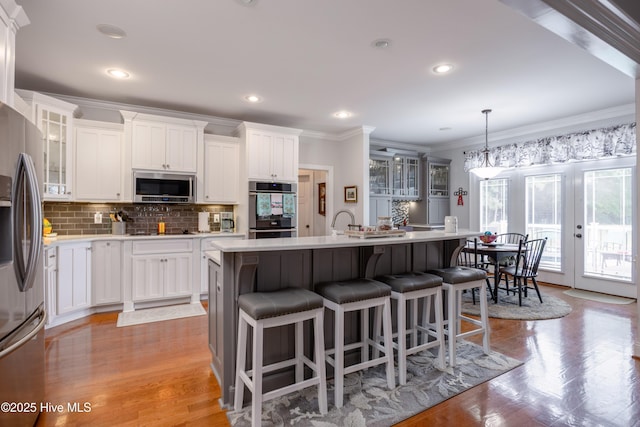 844 E Darden Rd, Faison, NC 28341 - kitchen with appliances with stainless steel finishes, crown molding, an island with sink, tasteful backsplash, and glass insert cabinets