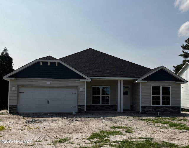 1217 Pelican Dr, New Bern, NC 28560 - view of front of home featuring stone siding, an attached garage, and a shingled roof