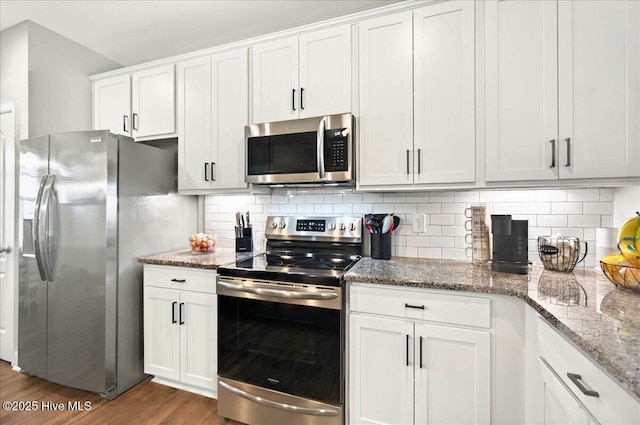 5735 Orchardgrass Rd, Leland, NC 28451 - kitchen with appliances with stainless steel finishes, wood finished floors, white cabinets, backsplash, and light stone countertops