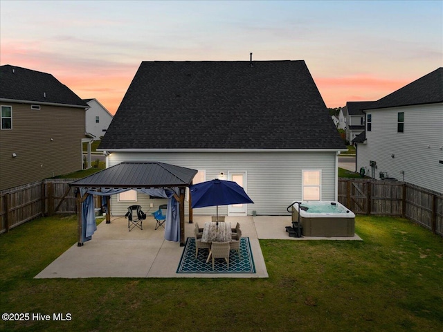 5735 Orchardgrass Rd, Leland, NC 28451 - back of property at dusk featuring a gazebo, a hot tub, a patio, and a shingled roof