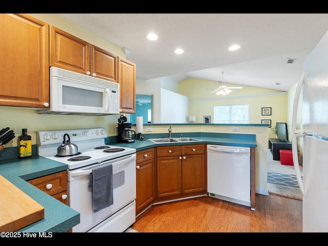 4043 Brick Path Ln SE, Southport, NC 28461 - kitchen featuring white appliances, a sink, a peninsula, light wood-style floors, and brown cabinetry