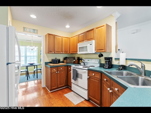 4043 Brick Path Ln SE, Southport, NC 28461 - kitchen featuring white appliances, ornamental molding, a sink, a chandelier, and light wood-style floors