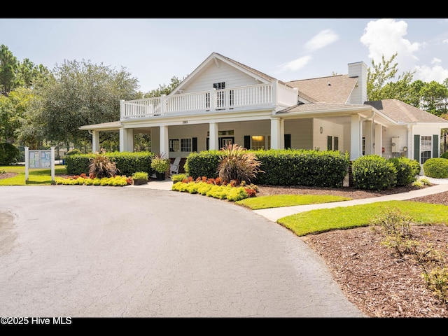 4043 Brick Path Ln SE, Southport, NC 28461 - view of front of house featuring a balcony, a chimney, and a shingled roof