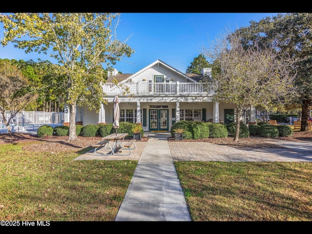 4043 Brick Path Ln SE, Southport, NC 28461 - view of front of house with french doors, a front lawn, and a chimney