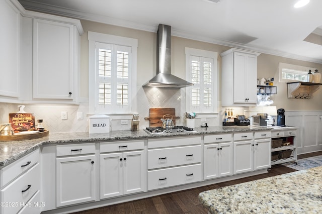 3020 Eno Ln, Leland, NC 28451 - kitchen with wall chimney exhaust hood, white cabinets, ornamental molding, stainless steel gas stovetop, and dark wood-style floors