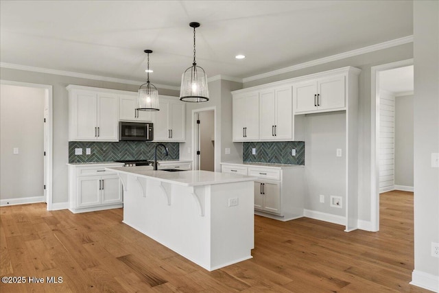 2259 Heartland Rd, Battleboro, NC 27809 - kitchen with white cabinetry, an island with sink, ornamental molding, light countertops, and backsplash