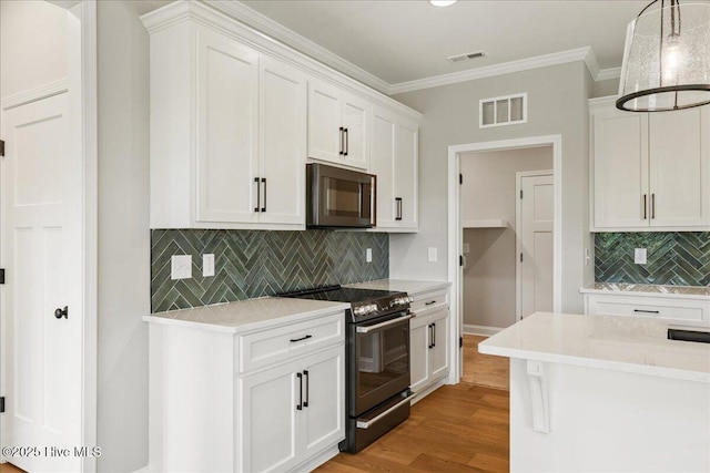 2259 Heartland Rd, Battleboro, NC 27809 - kitchen featuring stainless steel microwave, black range with electric stovetop, white cabinets, decorative backsplash, and light wood-type flooring