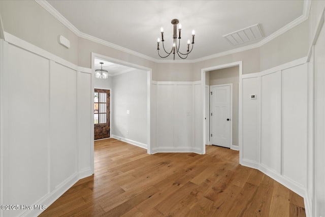 2259 Heartland Rd, Battleboro, NC 27809 - unfurnished dining area featuring a chandelier, ornamental molding, a decorative wall, and light wood-style floors